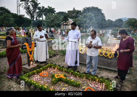 Kolkata, Indien. 02 Nov, 2016. Ein Priester Gebete rezitieren als Familie ist für Ihre verstorbenen Verwandten auf einem Friedhof in Kalkutta betet, Indien während Allerseelen. Credit: argha Chowdhury/alamy leben Nachrichten Stockfoto