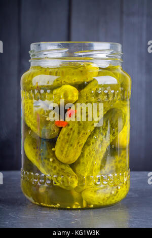 Eingelegte Gurken oder Gurken im Glas auf einem grauen Hintergrund. Stockfoto