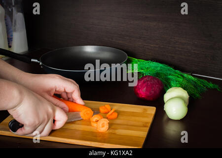Vorbereitung der ukrainischen Suppe - borsch. Reinigung und schneiden Kartoffeln Karotten Stockfoto
