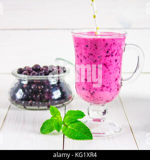 Smoothies von schwarzen Johannisbeeren in einem Glas mit einem Griff auf einem weißen Tisch Stockfoto