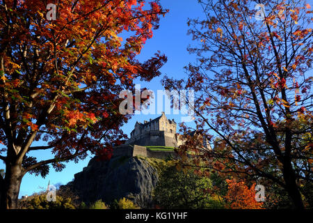 Das Edinburgh Castle ist von den Herbstfarben der Bäume in den Princes Street Gardens umgeben. Stockfoto