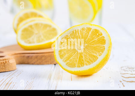 Ein Becherglas und einen Krug kalten Limonade auf einem weißen Hintergrund Holz umgeben von Zitronen Stockfoto