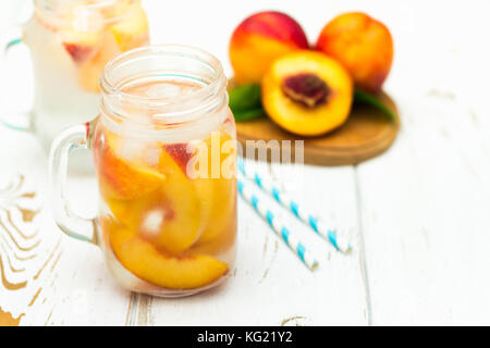 Hausgemachte Eistee Limonade mit reife Pfirsiche. Frischer pfirsich Eistee in einem Marmeladenglas. Stockfoto