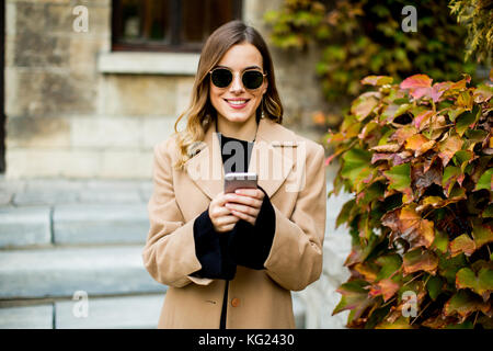 Porträt der jungen Frau mit Mobiltelefon im Herbst im Freien Stockfoto