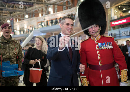 Der neue Verteidigungsminister Gavin Williamson dirigiert die Band der Grenadier Guards am London Poppy Day am Londoner Bahnhof Waterloo bei seinem ersten öffentlichen Auftritt seit seiner heutigen Ernennung. Stockfoto