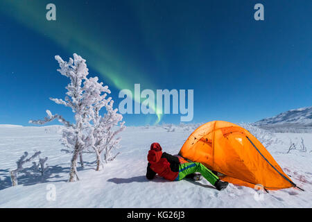 Wanderer außerhalb ein Zelt sieht sich die Nordlichter (Aurora Borealis), abisko, Norrbotten County, Gemeinde Kiruna, Lappland, Schweden, Skandinavien Stockfoto