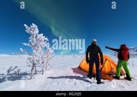 Wanderer außerhalb der Hütte Blick auf die Nordlichter (Aurora Borealis), abisko, Norrbotten County, Gemeinde Kiruna, Lappland, Schweden, Skandinavien Stockfoto