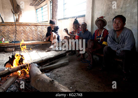 Naga Männer sitzen plaudernd runde Feuer im Dorf Muting (Saal), Nagaland, Indien, Asien Stockfoto