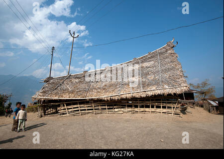 Naga Kinder neben kleinen Bambus gebaut, Fächerpalme mit Strohdach Murung (Versammlungssaal) mit traditionellem geschwungenem Dach, Nagaland, Indien, Asien Stockfoto