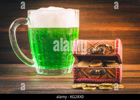 Eine Tasse grünen Bier auf den Tisch. Klee Blätter. Brust von Gold, Münzen Flor. St Patrick's Day Stockfoto