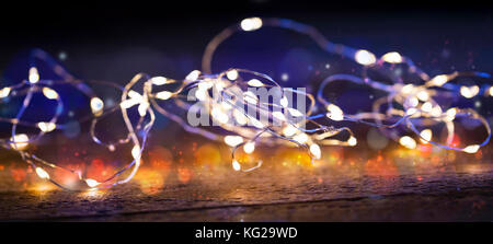 Festliche Weihnachtsbeleuchtung, Bokeh und geringer Tiefe Schwerpunkt glühenden Lichter Installation auf Holzbrett Stockfoto