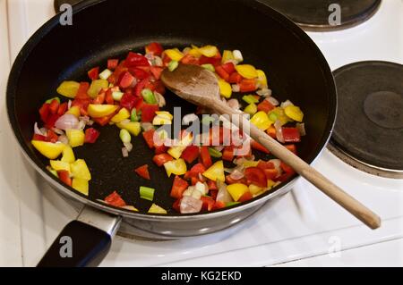 Eine paella Kochen auf dem Herd in einer Teflon beschichtete Wok mit Holzlöffel Stockfoto