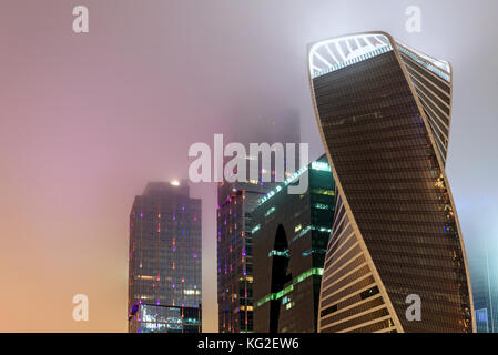 Abstrakte hi-tech-Hintergrund von Fragment moderne elevation Büro Gebäude aus Stahl und Glas mit Lichtern in der Nacht in die Nebelscheinwerfer eingeschaltet Stockfoto