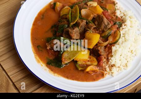 Hausgemachtes saag Gosht Rind Curry mit weißem Reis auf einem weißen Teller auf Eichentisch Stockfoto