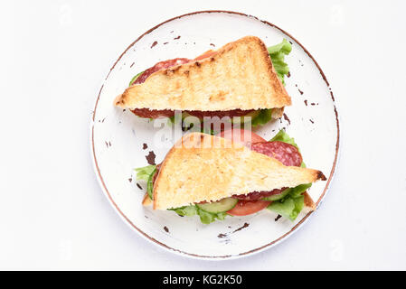 Zwei Brötchen mit Salami, Tomaten, Gurken und Salat auf die Platte über der weißen Stein Hintergrund, Ansicht von oben Stockfoto