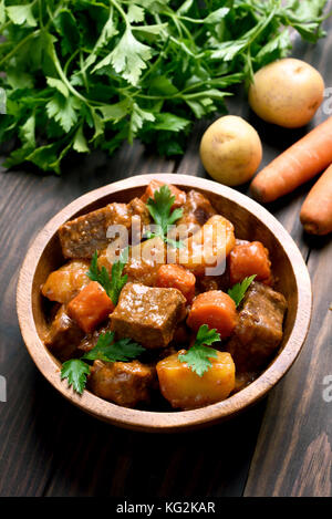 Gulasch, Fleisch Eintopf mit Gemüse in Schale auf Holztisch Stockfoto