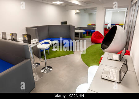 Modernes Büro mit Schreibtisch und Laptops; Lounge im Hintergrund. Stockfoto