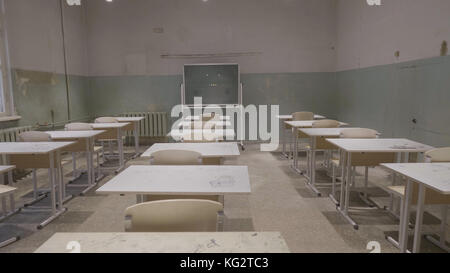 Leeres Klassenzimmer mit Holzschreibtischen, weißen und grünen Kreidebrettern in der Schule. Leerer Schulungsraum. Verlassener Schulraum mit Schreibtischen und Tafel Stockfoto