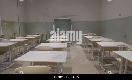 Leeres Klassenzimmer mit Holzschreibtischen, weißen und grünen Kreidebrettern in der Schule. Leerer Schulungsraum. Verlassener Schulraum mit Schreibtischen und Tafel Stockfoto