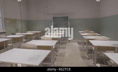 Leeres Klassenzimmer mit Holzschreibtischen, weißen und grünen Kreidebrettern in der Schule. Leerer Schulungsraum. Verlassener Schulraum mit Schreibtischen und Tafel Stockfoto