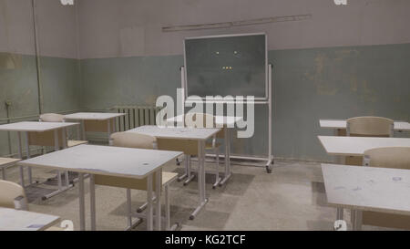 Leeres Klassenzimmer mit Holzschreibtischen, weißen und grünen Kreidebrettern in der Schule. Leerer Schulungsraum. Verlassener Schulraum mit Schreibtischen und Tafel Stockfoto