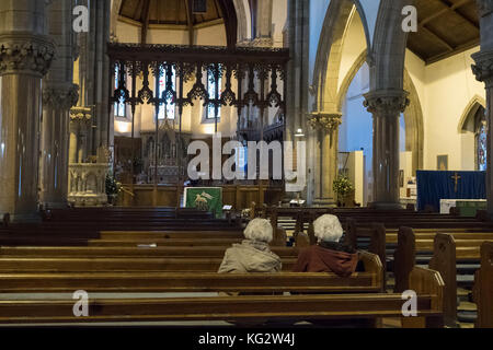 Zwei ältere Damen, die in leeren Kirchenbänken in der Inverness Cathedral, Inverness, Schottland, Großbritannien, sitzen Stockfoto