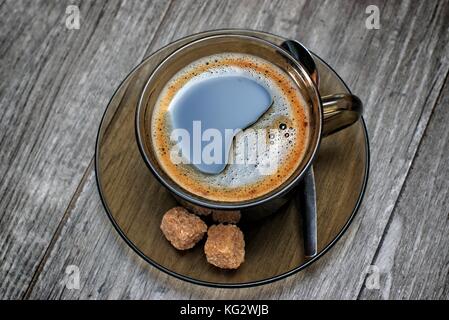 Tasse Kaffee mit braunem Zucker auf hölzernen Tisch. Stockfoto