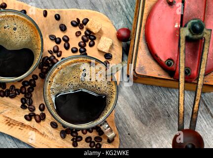 Zwei Tassen Kaffee, Kaffeebohnen, Braune Klumpen Zucker und Kaffee Schleifer auf Holz- Hintergrund. Stockfoto