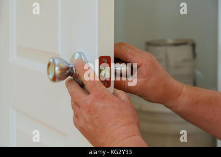 Nahaufnahme eines professionellen Bauschlosser installieren oder Reparieren eines neuen deadbolt Verschluss auf eine Haustür mit der Innenseite interne Teile des Schließmechanismus sichtbar. Stockfoto