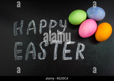 Schiefertafel mit den Worten frohe Ostern und Eier. Stockfoto