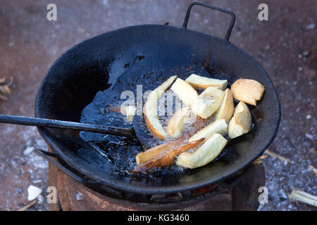 Frittieren Cassava in Öl in einer Pfanne auf Feuer Herd. Foto im Najja, Uganda am 9. Mai 2017 berücksichtigt. Stockfoto