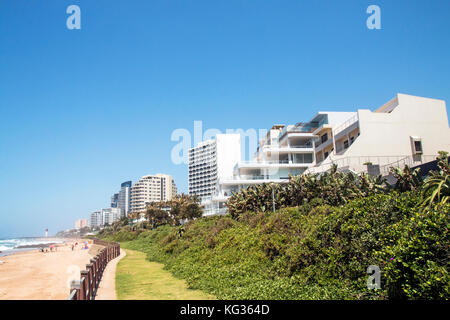 Küstenlandschaft von grünen Dünenvegetation Strand und Meer gegen Gewerbe- und Wohnbauten und blauer Himmel in Umhlanga in der Nähe von Durban in Südafrika af Stockfoto