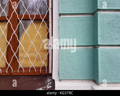Mauer der Stadt Haus, grüner Stein Blöcke, ein Fenster mit Holzrahmen und einem vintage Metall Grill. Stockfoto