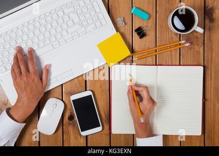 Geschäftsfrau mit Laptop und auf ihr Büro Tabelle Stockfoto