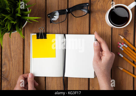 Geschäftsfrau auf der Suche leer notebook Seiten auf hölzernen Schreibtisch Stockfoto