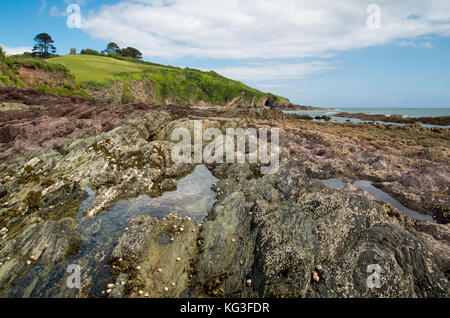 Ein Meer vies von einem felsigen Ufer in Talland Bucht bei Ebbe mit kleinen Pools von Wasser in den Felsen. Stockfoto