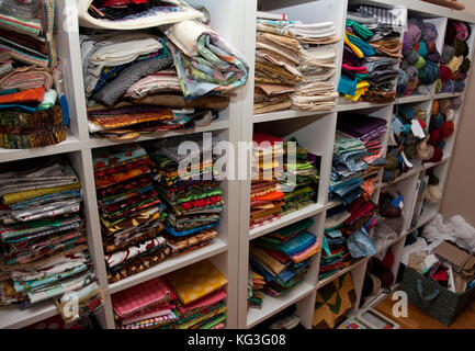 Eine Wand voller Regale mit bunten Nähen und Quilten Gewebe und stricken Wolle in ein Handwerk Zimmer Stockfoto