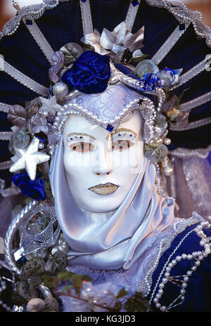 Italien. Venedig. Karneval. Frau in Kostüm. Nahaufnahme des Gesichts mit weißer Maske.