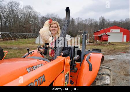 Landwirtin auf Traktor mit Huhn auf der Wise Acres Organic Farm, einem U-Pick-Erdbeer-Landwirtschaftsbetrieb im Indian Trail, North Carolina, USA Stockfoto