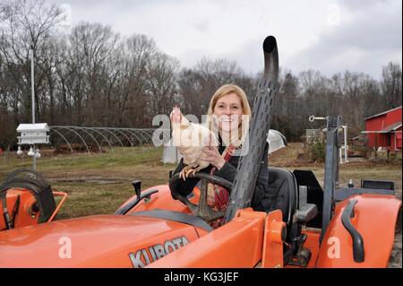 Landwirtin auf Traktor mit Huhn auf der Wise Acres Organic Farm, einem U-Pick-Erdbeer-Landwirtschaftsbetrieb im Indian Trail, North Carolina, USA Stockfoto