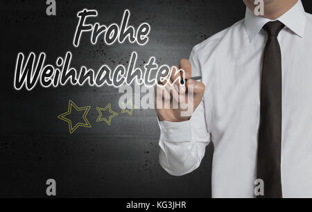 Frohe Weihnachten Frohe Weihnachten (in deutscher Sprache) wird durch Geschäftsmann geschrieben. Stockfoto