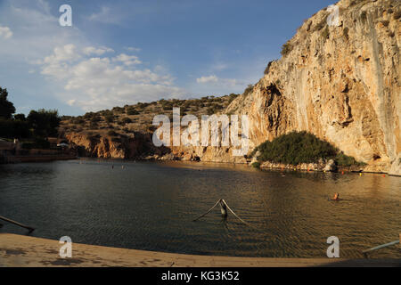 Vouliagmeni Athen Griechenland Touristen, die im Vouliagmeni-See schwimmen, ein Naturbad - war einst eine Höhle, aber das Höhlendach fiel durch Erosion durch die hohe Temperatur des fließenden Wassers ein. Stockfoto