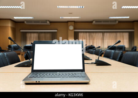 Weiße leere Laptop auf hölzernen Tisch im leeren Raum platziert. Stockfoto