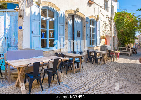 HDR-Bild-Blick auf Café und Restaurant mit Tischen und Stühlen in Alacati engen Steinstraßen, ein beliebtes Reiseziel für Reisen und Urlaub in Izmir Stockfoto