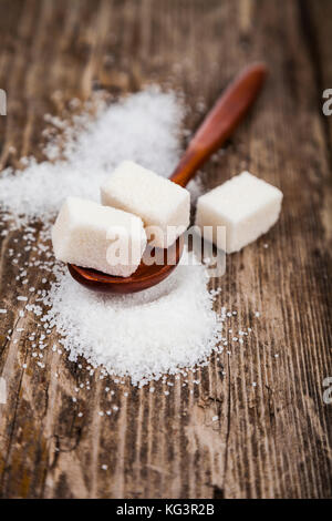 Löffel aus Holz mit Zucker auf einem alten Holz- Hintergrund Stockfoto