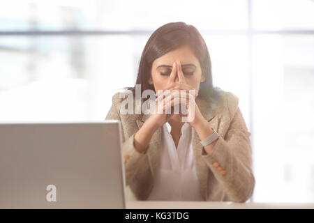 Betonte geschäftsfrau am Laptop mit Kopf in den Händen Stockfoto