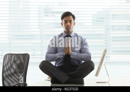 Geschäftsmann, Meditieren, auf dem Schreibtisch im Büro Stockfoto