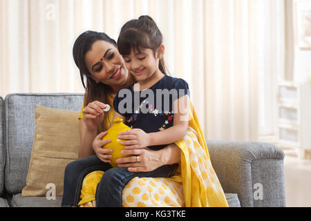 Mutter und Tochter Münzen im Sparschwein Stockfoto