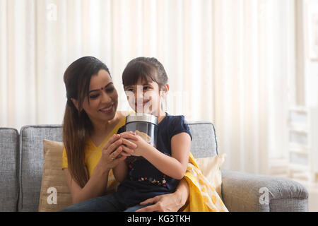 Lächelnde Mutter und Tochter Holding coin Box Stockfoto