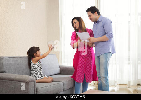 Mutter und Vater holding Dokumente und Tochter sitzen auf einem Sofa, Geld, Stockfoto